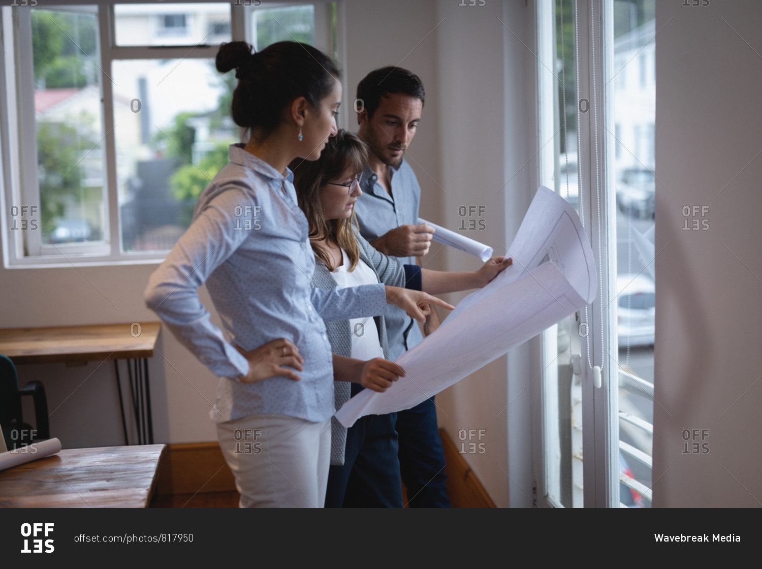 Side view of Diverse business people interacting with each other while looking at blueprint in the office