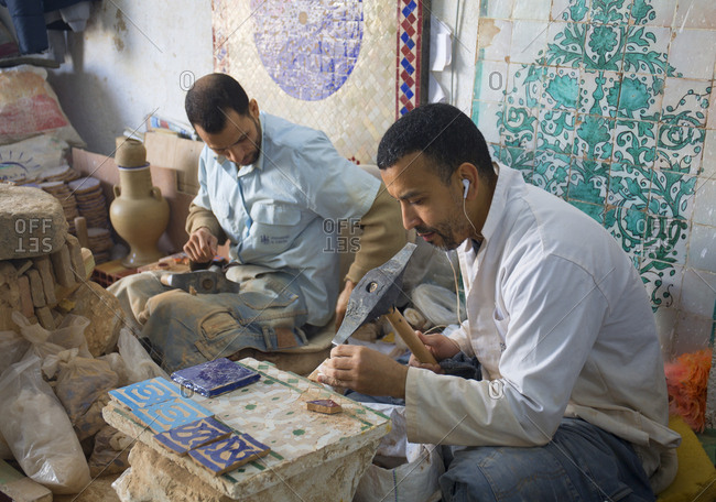 Fes, Morocco - April 6, 2019: Pottery and tile workshop, men making mosaic wall hanging and patio elements for sale to tourists.