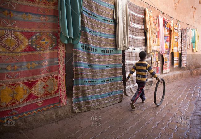 Taourirt Kasbah, Morocco - April 12, 2019: Young boy playing with bicycle tire in market