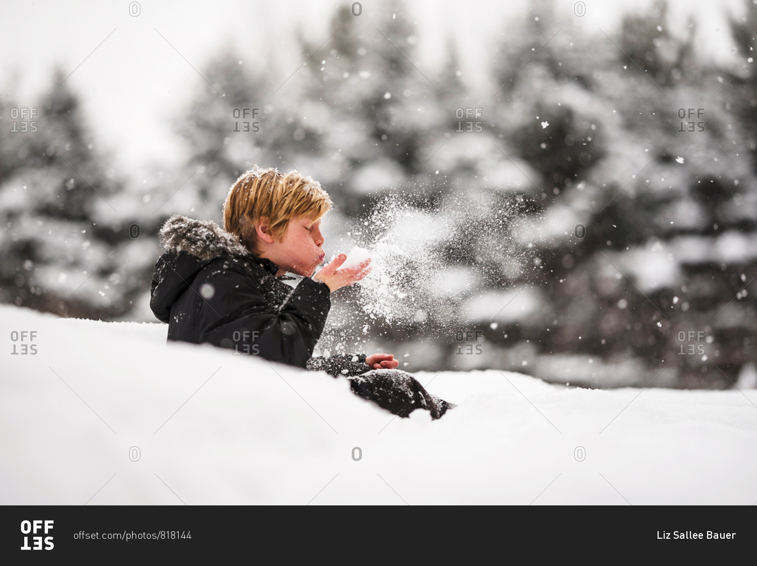 Portrait of a young boy blowing snow from his hands