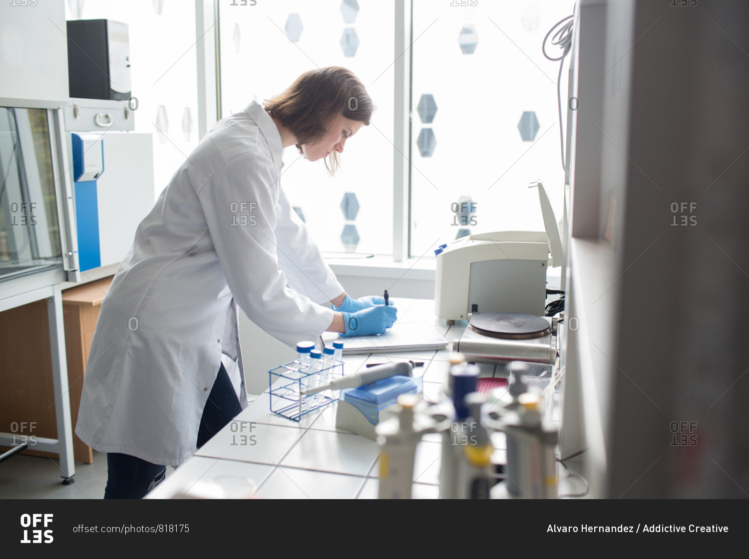 Side view of woman at table and taking notes in laboratory.