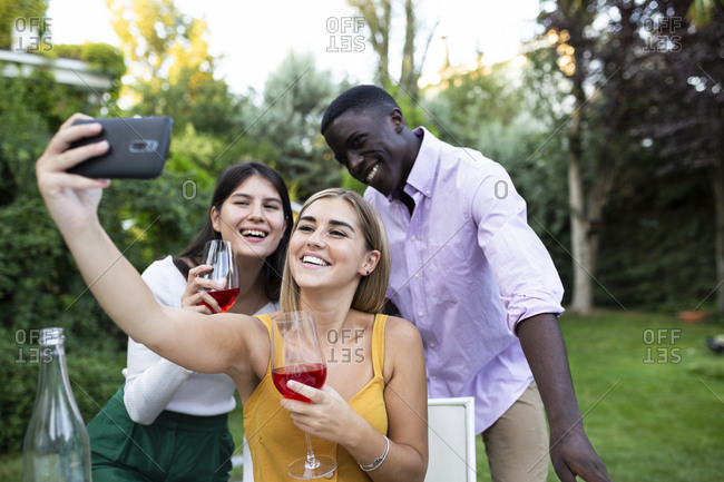 Friends having fun at a summer dinner in the garden- taking selfies