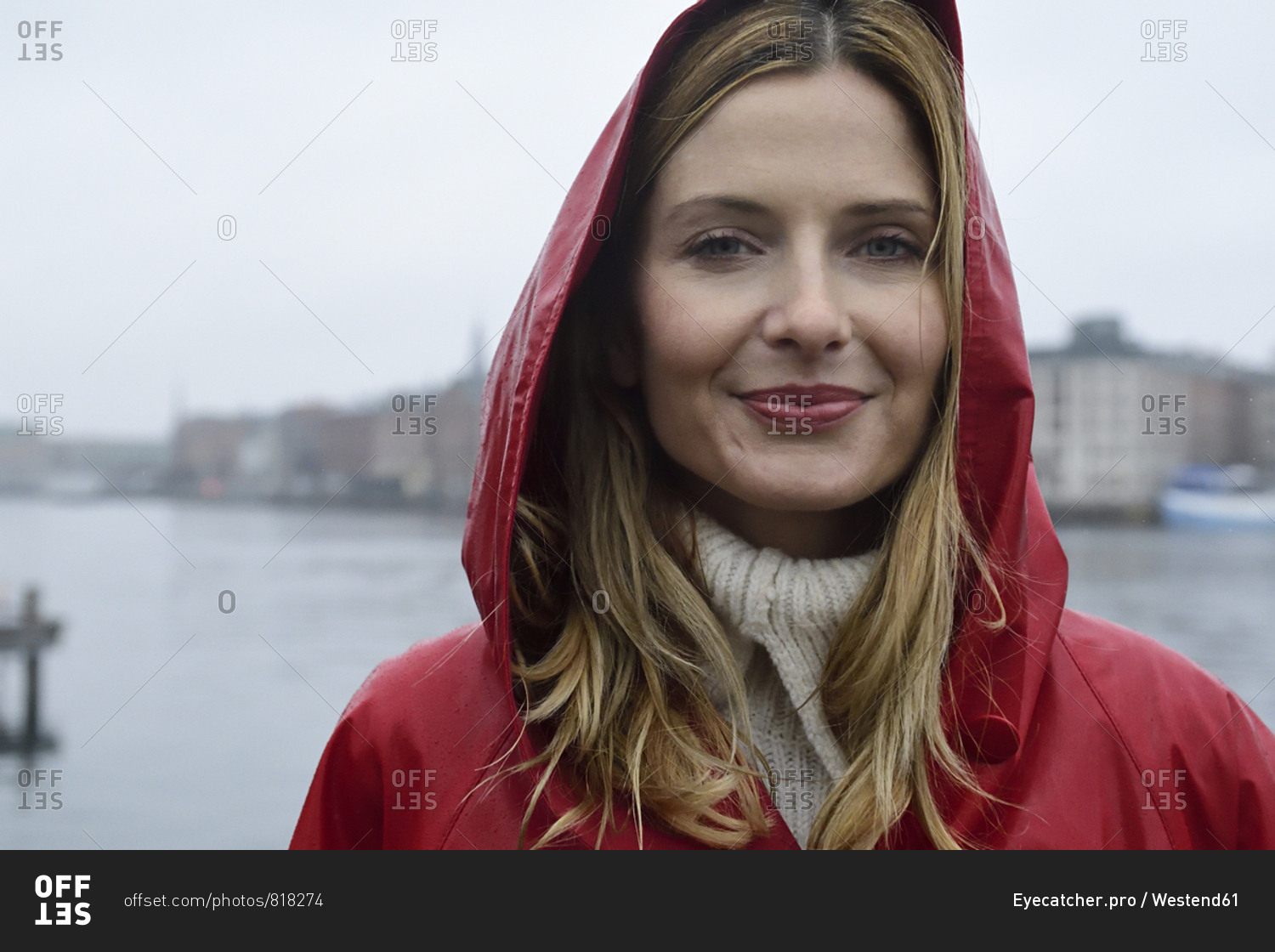Denmark- Copenhagen- portrait of smiling woman at the waterfront in rainy weather