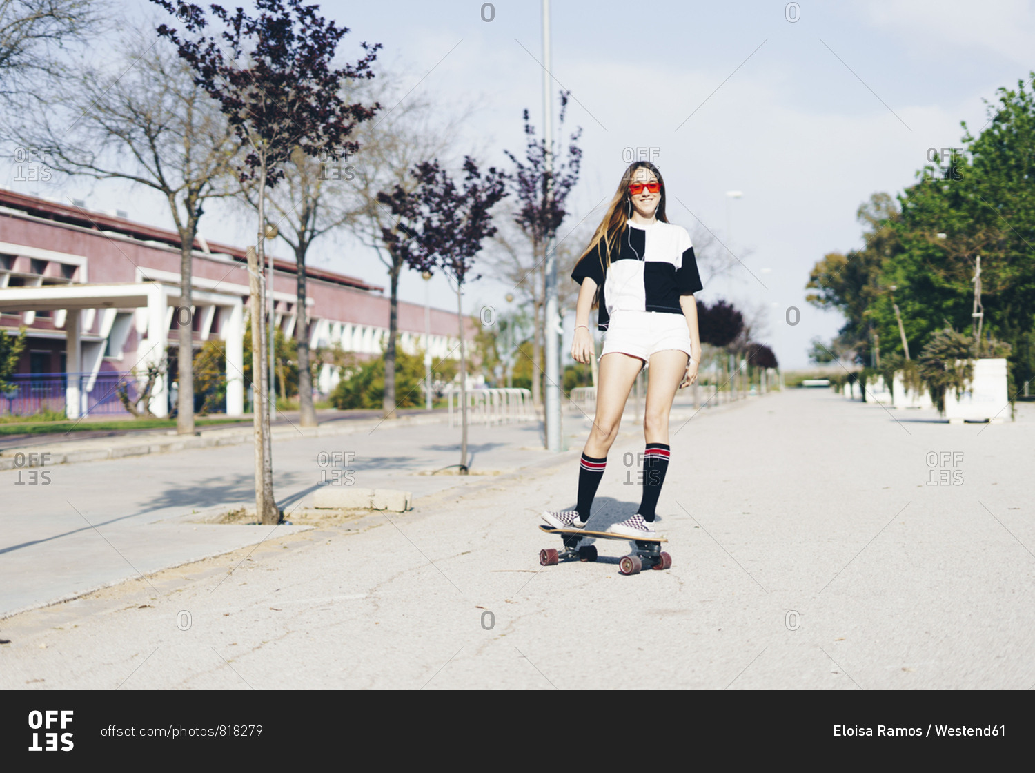 Spain- teenage girl riding skateboard on a road
