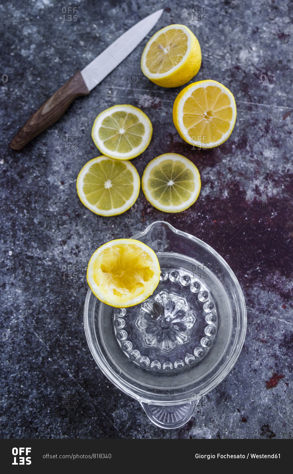 Lemon halves and slices and squeezed lemon half with litchen knife and lemon squeezer