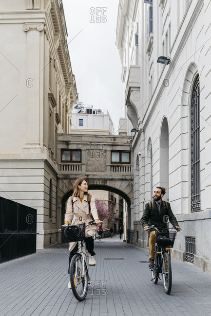 Smiling couple riding e-bikes in the city