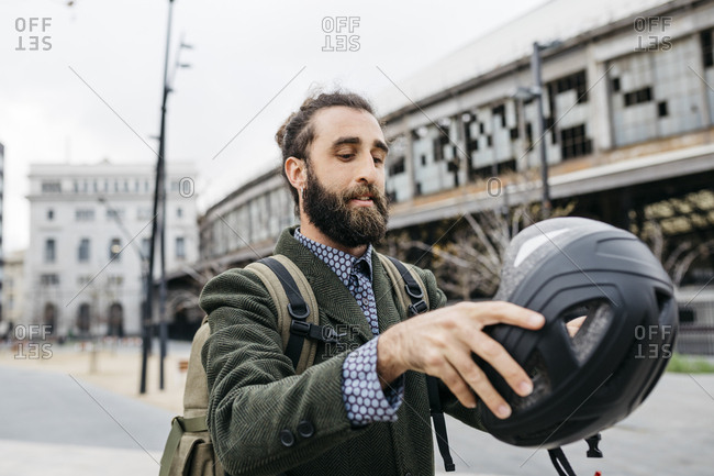 Portrait of man putting on bicycle helmet in the city