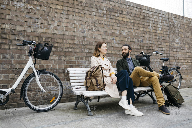 Couple sitting on a bench next to e-bikes talking