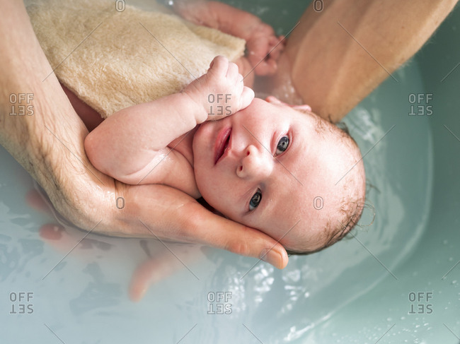 Man bathing newborn girl in a tub
