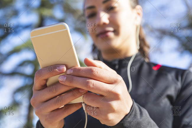 Close-up of young woman training and checking her smartphone