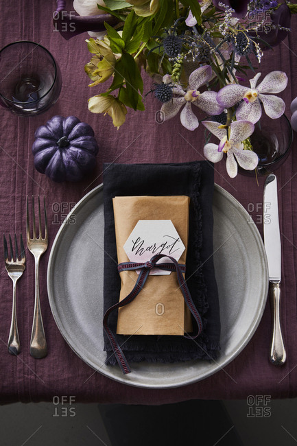 Plate set with a name tag on a purple tablecloth with flowers.