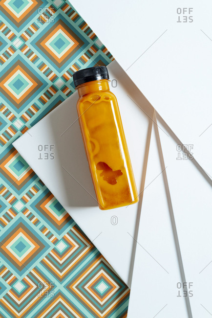 Mango and pumpkin smoothie bottle over retro style geometric textures. From above