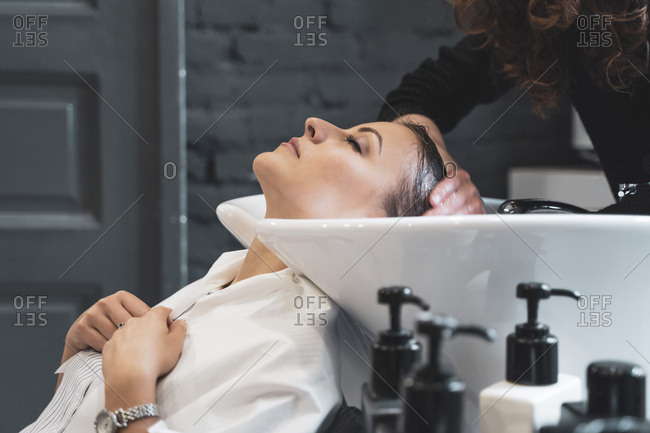 Stylist washing hairs to young lady