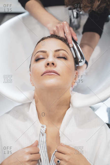 Stylist washing hairs to young lady