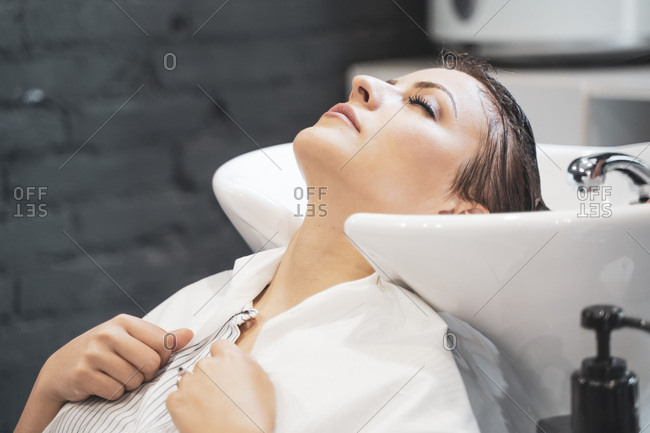 Stylist washing hairs to young lady
