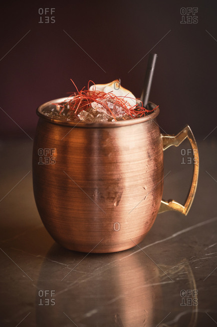 Metal mug of tasty cocktail with saffron and burnt marshmallow placed on counter in bar