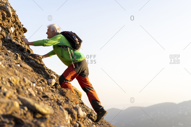 Senior man hiking a mountain during sunny day