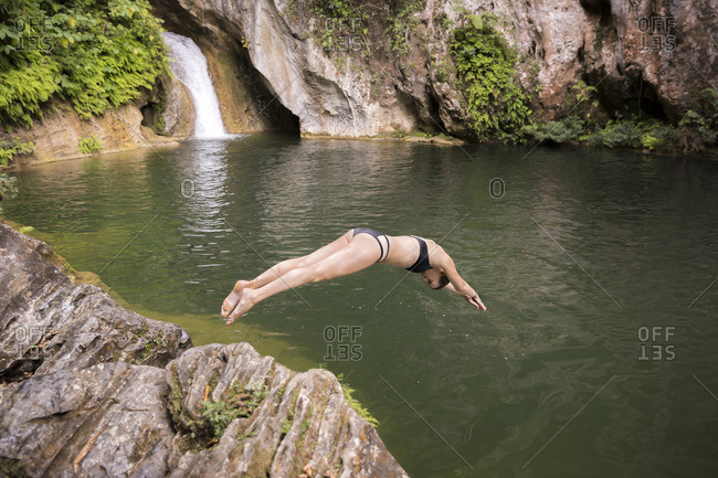 A woman dives into a pool with a waterfall near Trinidad, Cuba.