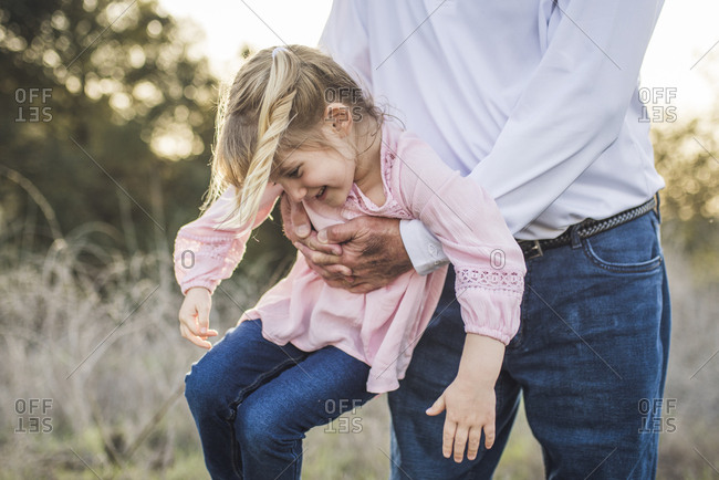 Granddaughter being swung by grandfather, playing in field