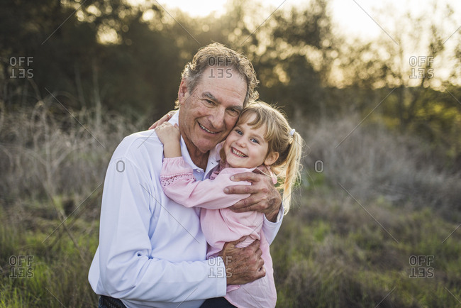 Granddaughter being swung by grandfather, playing in field