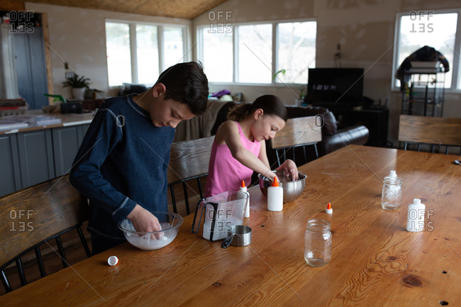 Kids making homemade slime with glue together at table