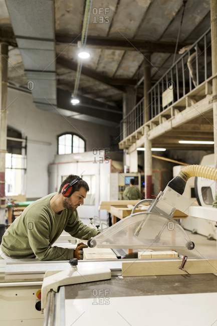 Carpenter using sawing machine in his workshop