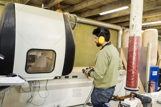 Carpenter using wood carving machine in a workshop
