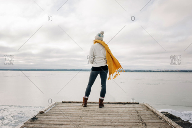 woman standing on the end of a pier jetty looking out to the water