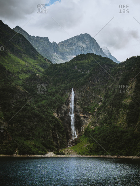 Big waterfall and blue lake between green mountain in Pyrenees