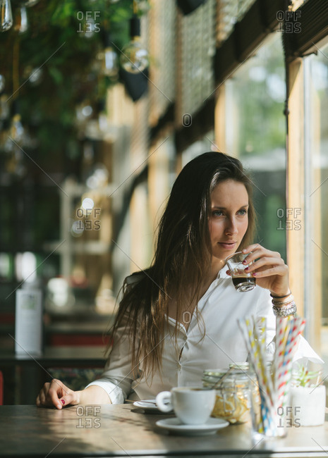 Beautiful Girl Sitting In A Cafe Drinking Espresso stock photo - OFFSET