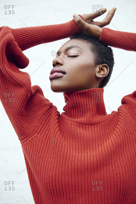 Young black woman with short brown hair poses in her red sweater