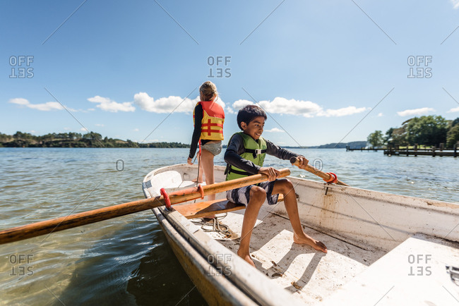 Two siblings in a rowboat on the lake in summer
