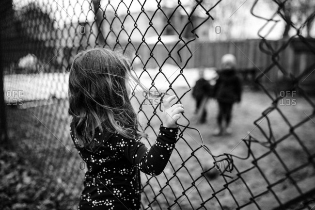 A girl talking with her friends through a fence.