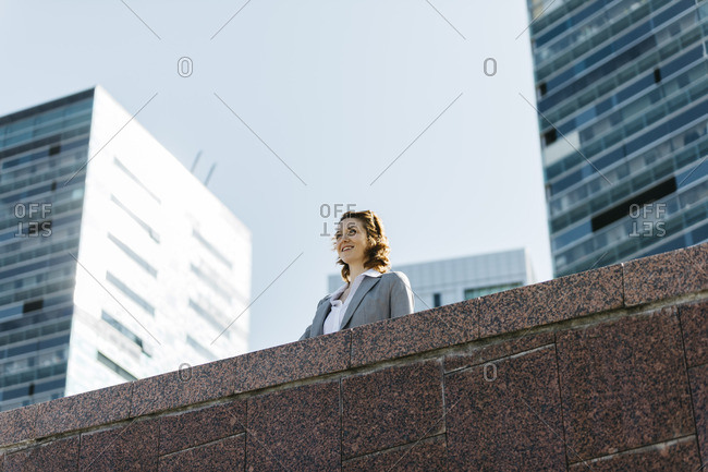 Successful young businesswoman standing at wall in front of office building