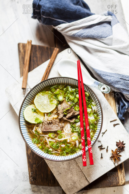 Bowl of Vietnamese Pho with rice noodles- mung beans- cilantro- spring onions and limes