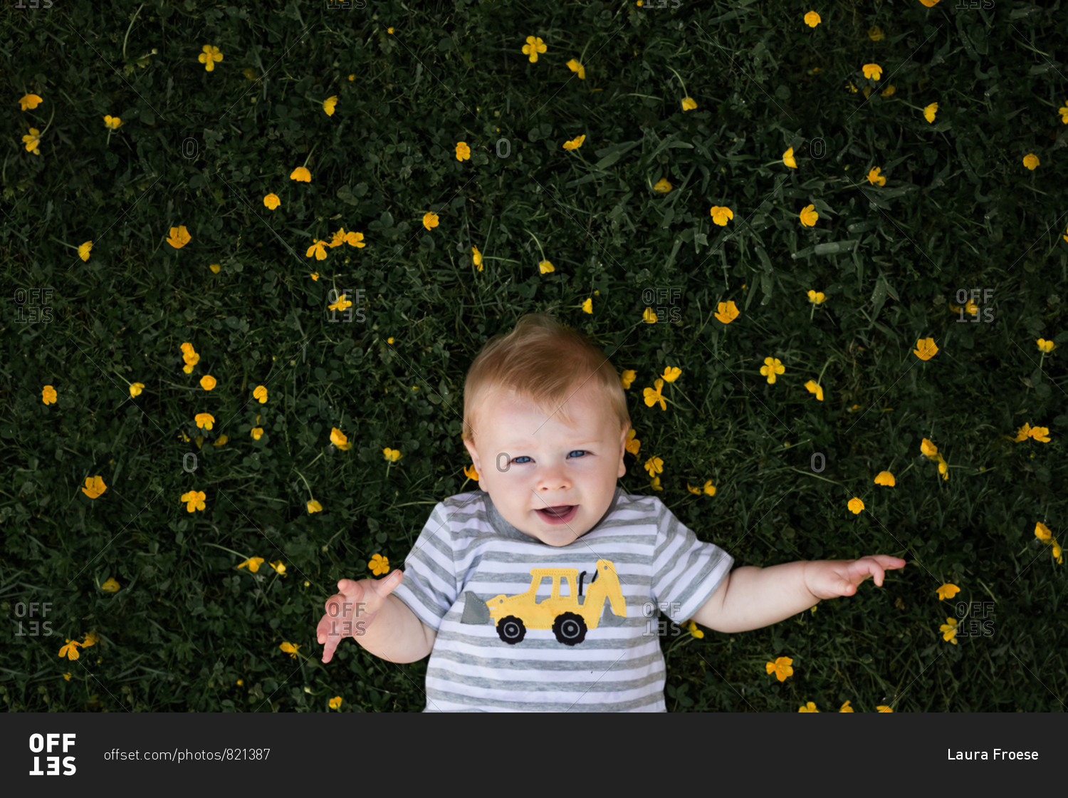 Young boy laying in grassy field with yellow flowers.