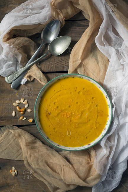 Bowl with delicious pumpkin puree placed on timber tabletop near spoons and napkins