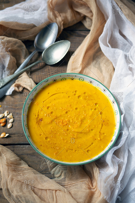 Bowl with delicious pumpkin puree placed on timber tabletop near spoons and napkins