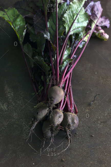 Bunch of fresh ripe beetroots with green leaves placed on gray surface