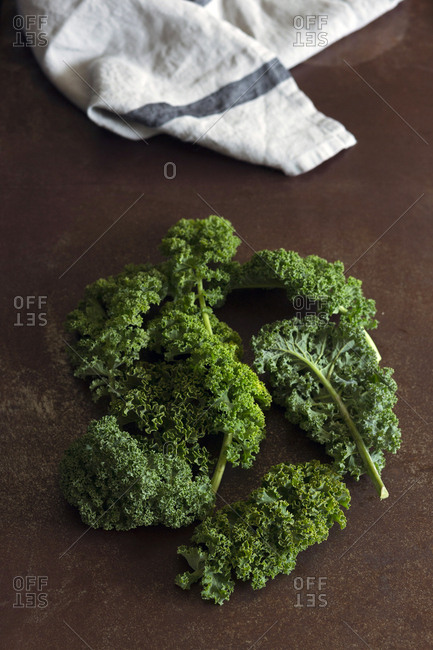 Heap of ripe leaf cabbage placed near napkin on red tabletop