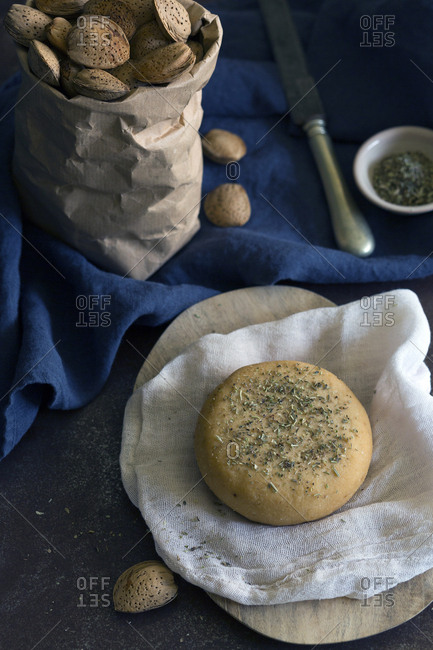Fresh almond bun with dried herbs placed on napkin on gray tabletop