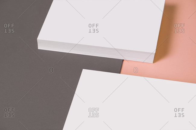 From above composition of heap of empty white business card template on grey and pink background