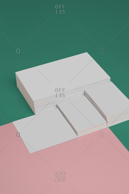 From above composition of heap of empty white business card template on green and pink background