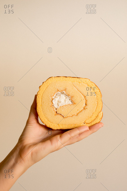 Hand holding slice of delicious fresh sweet banana cake on brown background
