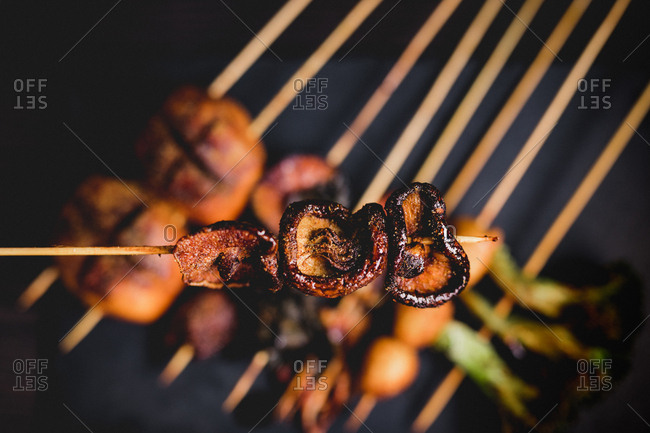From above cooked hot mushroom skewer over table with delicious grilled skewers with meat, fish, squid and broccoli