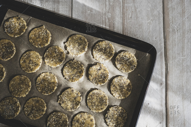 High angle close up of seeded cracker dough on a baking tray.