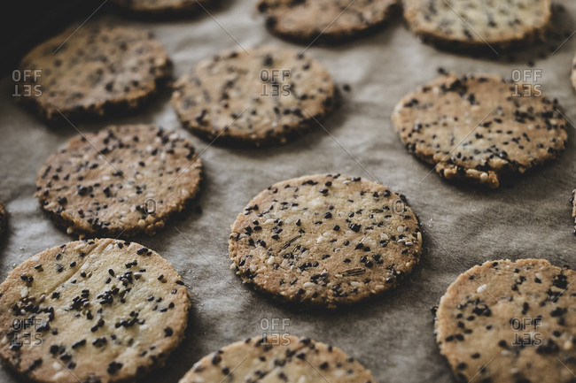 High angle close up of freshly baked seeded crackers on a baking tray.