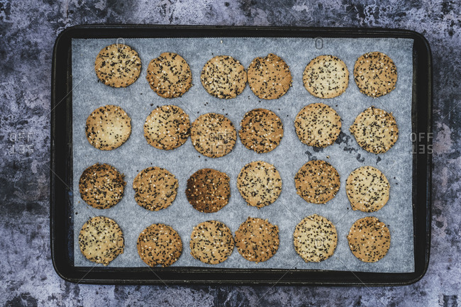 High angle close up of freshly baked seeded crackers on a baking tray.