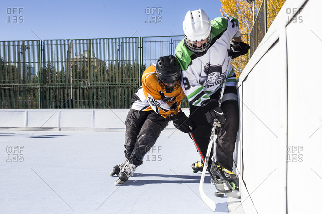 Two hockey players from opposite teams struggling for puck