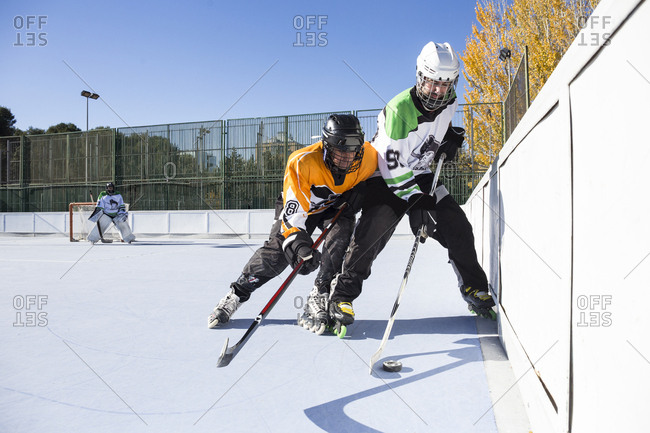 Two hockey players from opposite teams struggling for puck